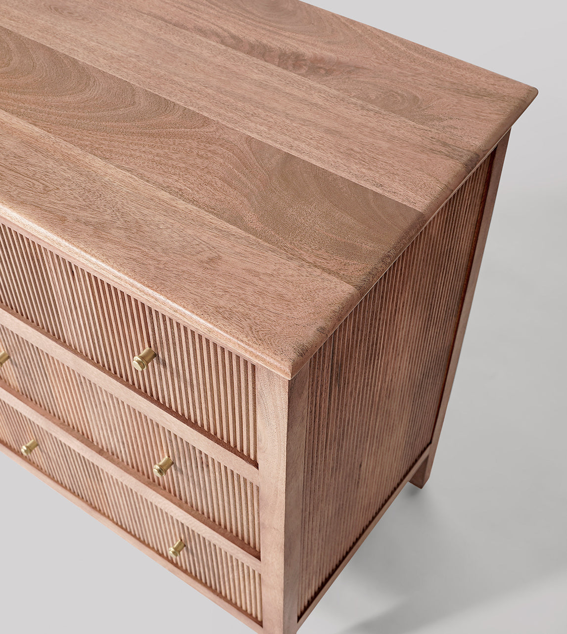 Wooden dresser with gold handles on a light gray background